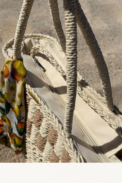 Cesto de palha à beira-mar com lenço de limões removível, segurado por uma mão com pulseira delicada.